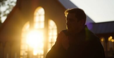 Bild eines Mannes, der bei Sonnenuntergang in der Nähe einer Kirche betet