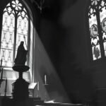 Schwarz-Weiß-Bild der Christusstatue in einer Kirche mit Licht, das durch das Fenster fällt